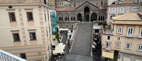 Une place historique, dominée par une église imposante, un clocher et un escalier menant à l’entrée de l’église.