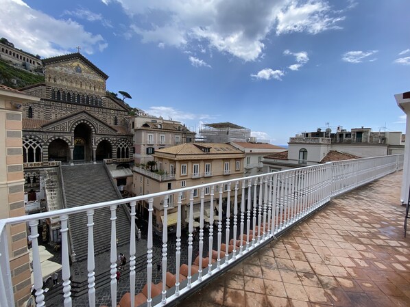 A view of a historic building with intricate architecture, a balcony with white balustrades, and a clear blue sky. - Terrazza Duomo (Amalfi)