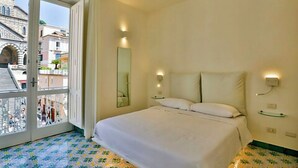 A hotel room with a large bed, a glass door leading to an outdoor balcony, and a city view. - Terrazza Duomo (Amalfi)