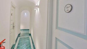 A hallway with a green patterned floor, a door with the number 207, and a fire extinguisher on the left. - Terrazza Duomo (Amalfi)