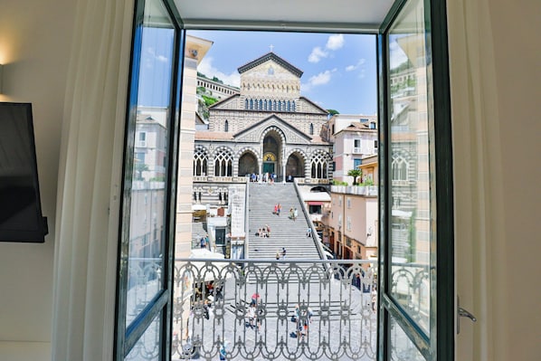 A view through a window of a building with a grand staircase leading to a large, ornate entrance. - Terrazza Duomo (Amalfi)