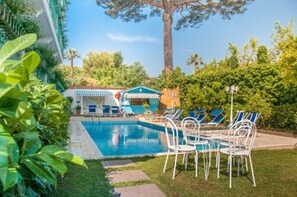 Una piscina al aire libre de temporada, tumbonas