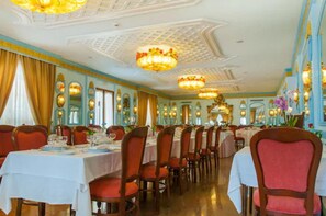 A formal dining room with multiple tables and chairs, ornate chandeliers, and decorative wall sconces. - Eliseo Park's (Sant'Agnello)
