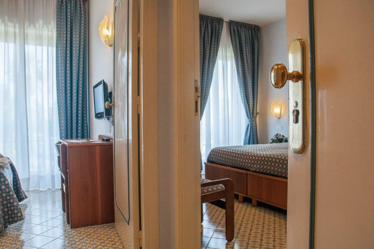 A hotel room with a bed, a desk, a chair, and a TV.