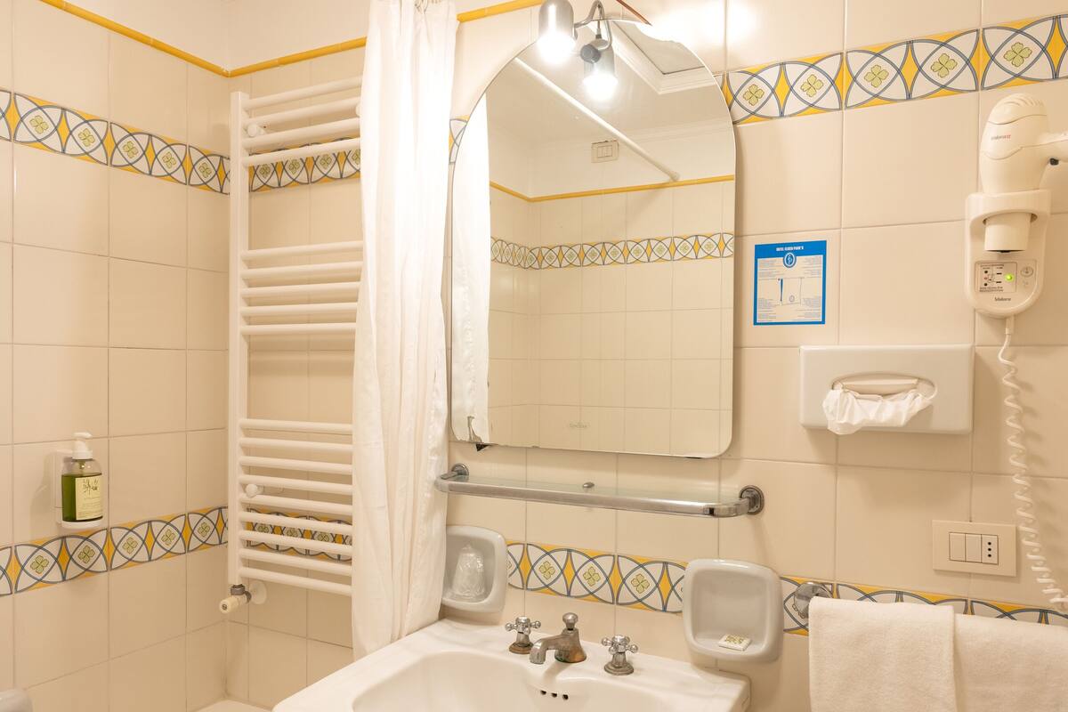 A bathroom with a bathtub, sink, and a hairdryer.