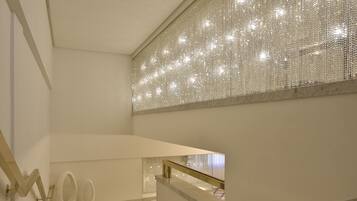 A modern interior with a staircase, white walls, and a decorative light fixture.