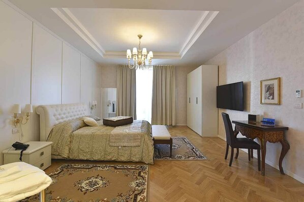 A hotel room with a large bed, a desk, a TV, and a chandelier. - Hotel Ariston (Capaccio-Paestum)