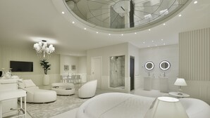 Una sala de estar moderna con una decoración en tonos blancos, un amplio espacio de descanso circular, una mesa de comedor y una escalera que sube a un nivel superior.