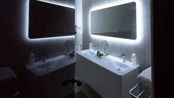 Un baño moderno con dos lavamanos, espejos y un perchero para toallas.