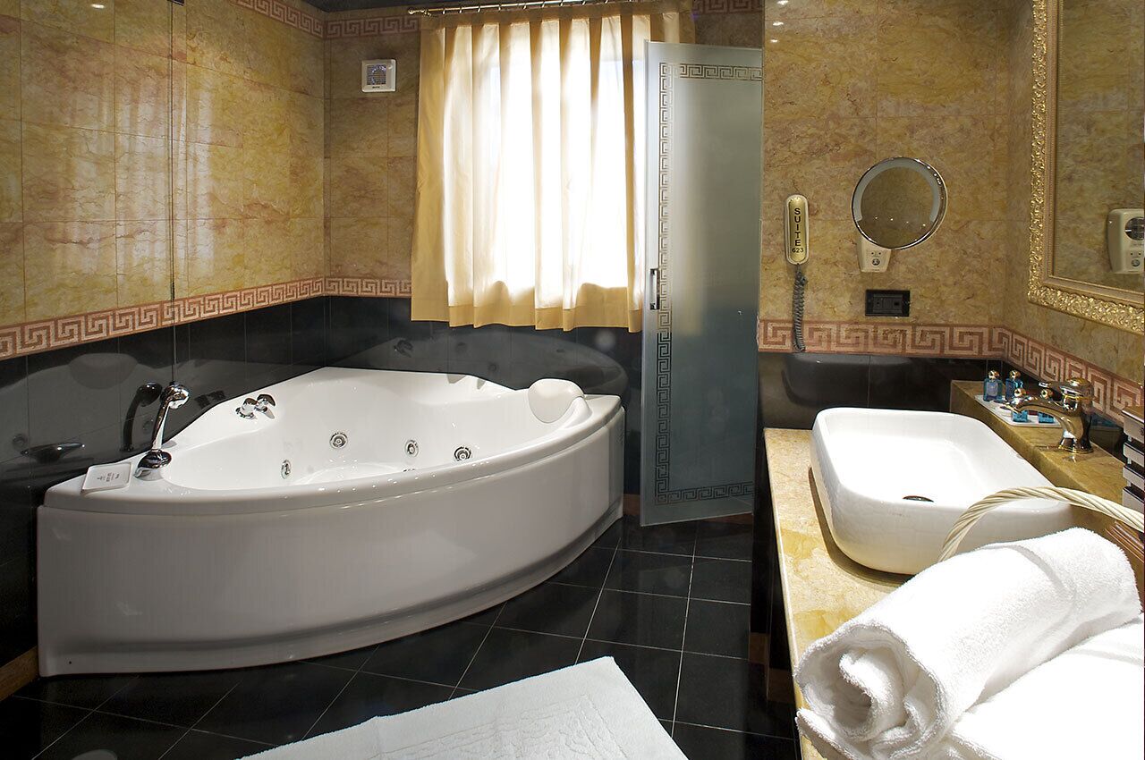 A bathroom with a large freestanding bathtub, a sink, a mirror, and a towel.