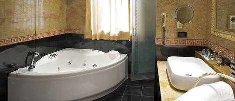 A bathroom with a large freestanding bathtub, a sink, a mirror, and a towel.