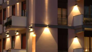 A multi-story building with balconies and exterior lighting.