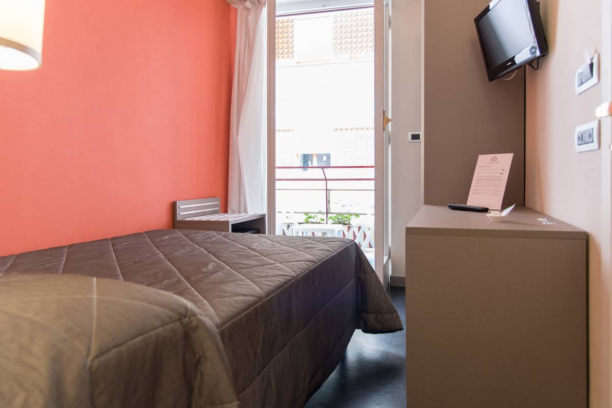 Ein Hotelzimmer mit Bett, Schreibtisch, Fernseher und Blick ins Freie.