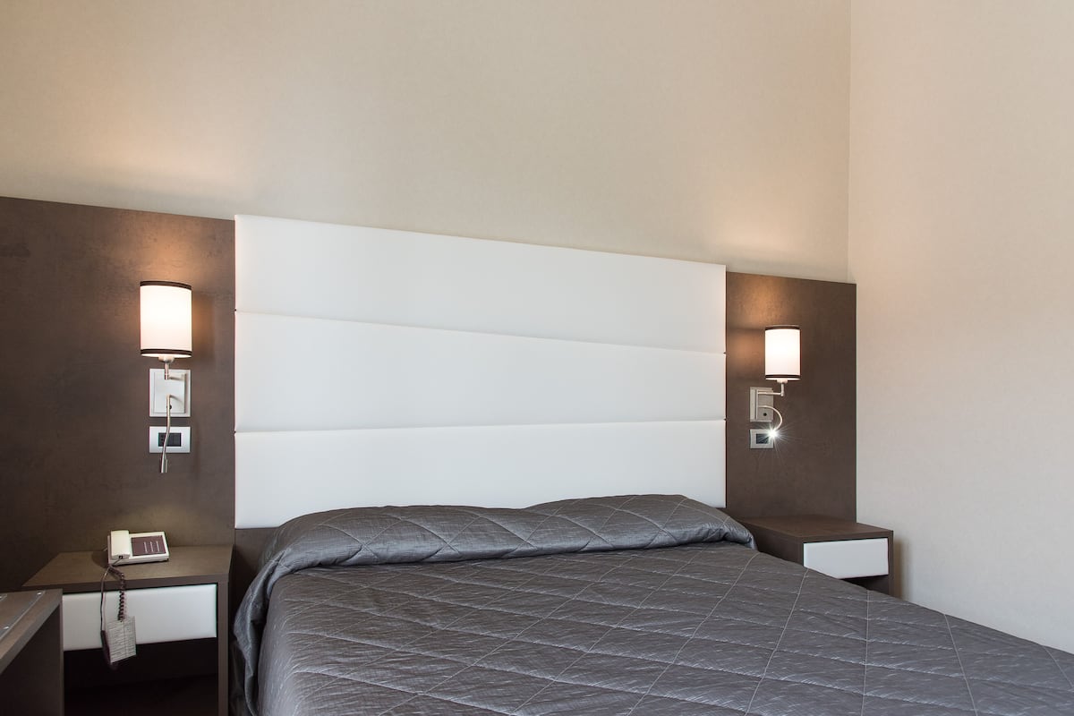 Ein Hotelzimmer mit Bett, Nachttischen und Wandlampen.