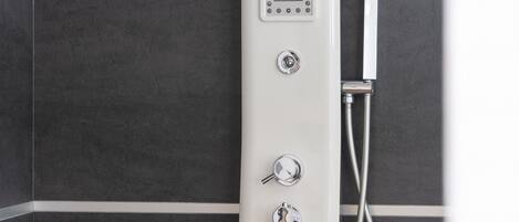 A modern shower with a control panel and a handheld showerhead against a tiled wall.