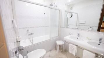 A bathroom with a toilet, a sink, a shower, and a mirror.
