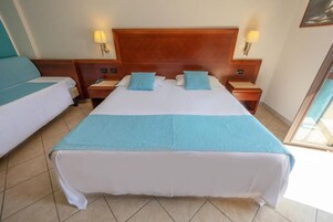 A hotel room with a large bed, two bedside tables, and two lamps.