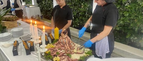 A buffet setup with seafood, candles, and a table set for dining.