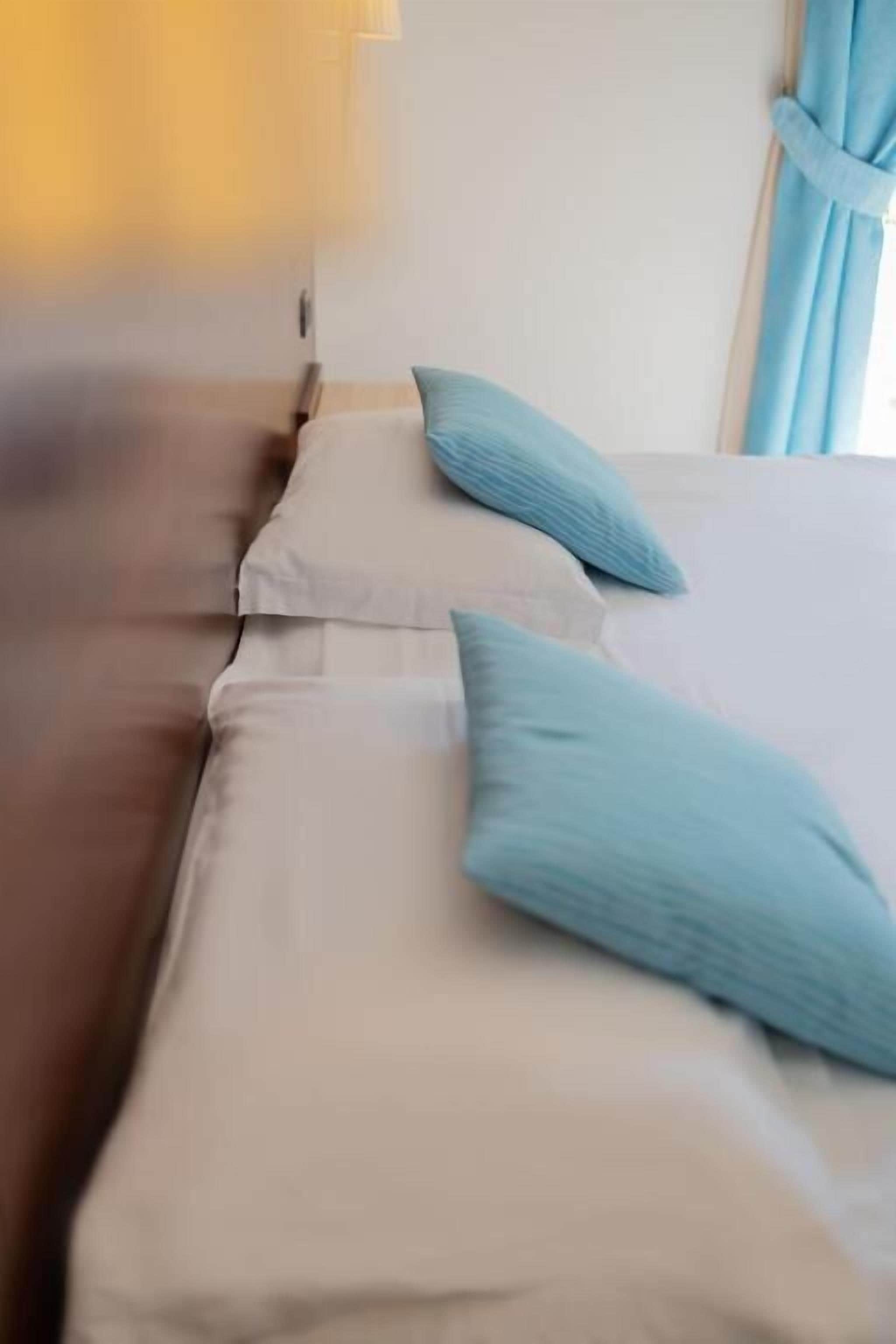 Una cama con ropa de cama color beige y dos almohadas azul claro.