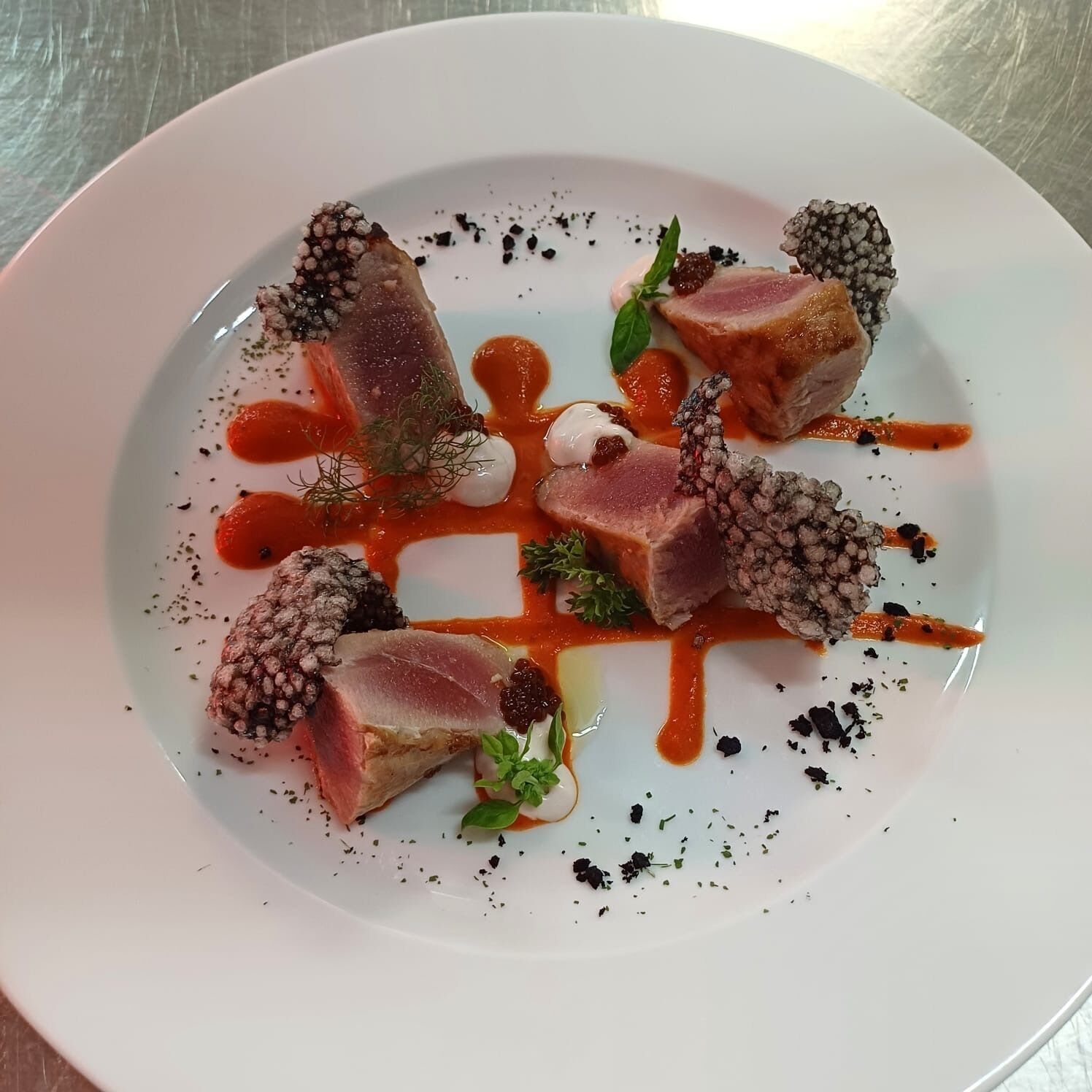 Une assiette blanche contenant un plat composé de viande, de baies et de sauce.