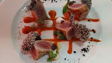 A white plate with a dish consisting of meat, berries, and sauce.