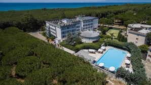 Vista aérea de un hotel con piscina, rodeado de vegetación y con vistas al mar.