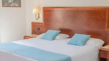 Una camera d'albergo con un letto grande, una testiera in legno, due comodini con lampade e un quadro appeso al muro.