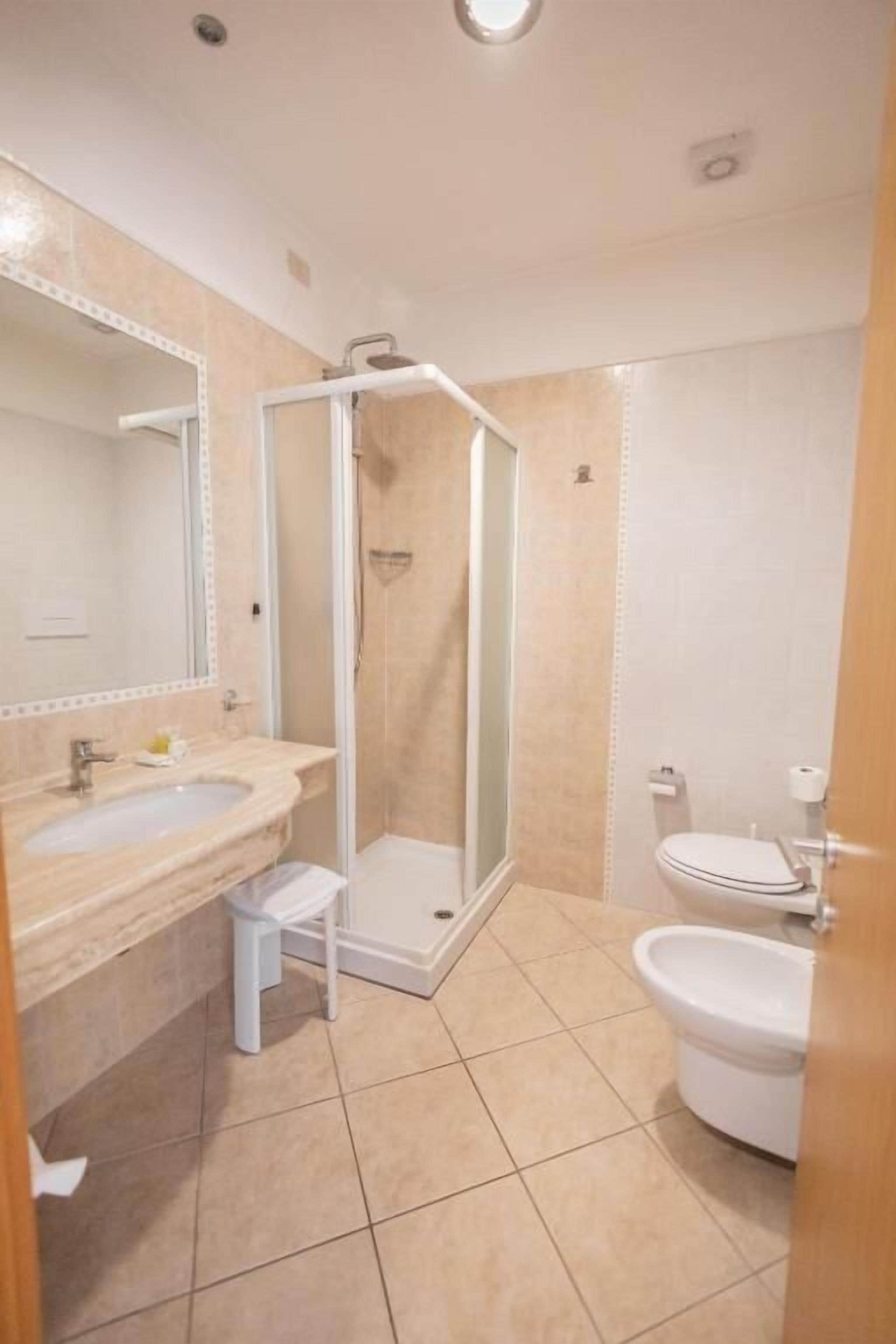 A bathroom with a shower, sink, and toilet.