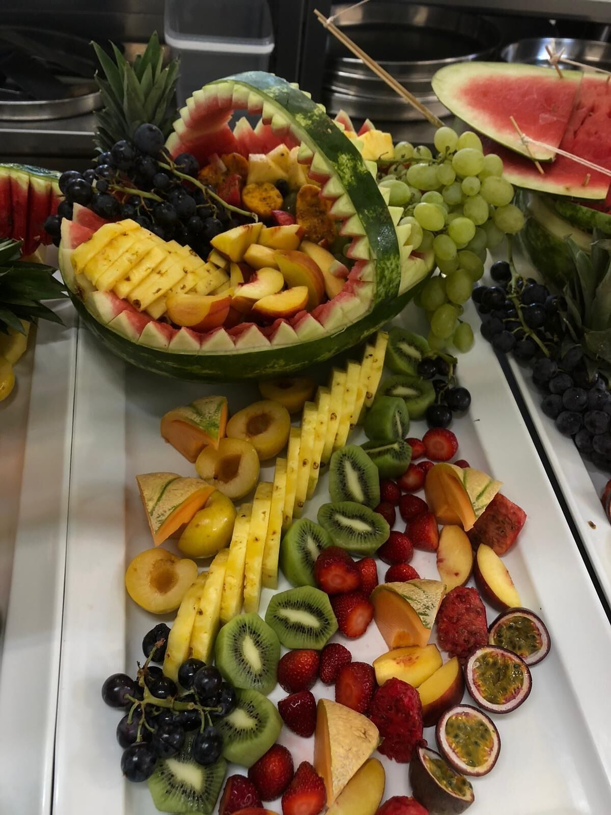 Un assortiment de fruits frais comprenant de la pastèque, des raisins, des fraises, des kiwis et de l’ananas.