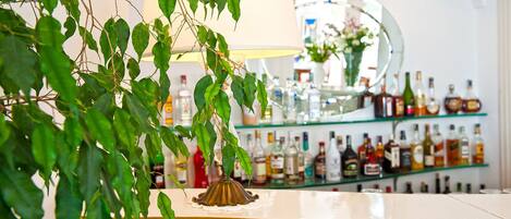 A bar area with a variety of liquor bottles on shelves, a decorative lamp, and a mirror reflecting the interior.