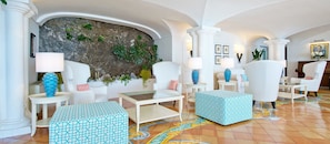A spacious lobby with white furniture, a stone wall, and a colorful tiled floor.