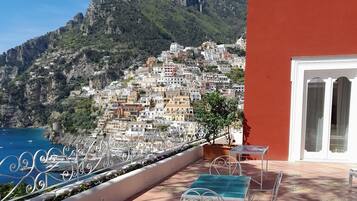 A terrace with outdoor seating and a view of a coastal town.