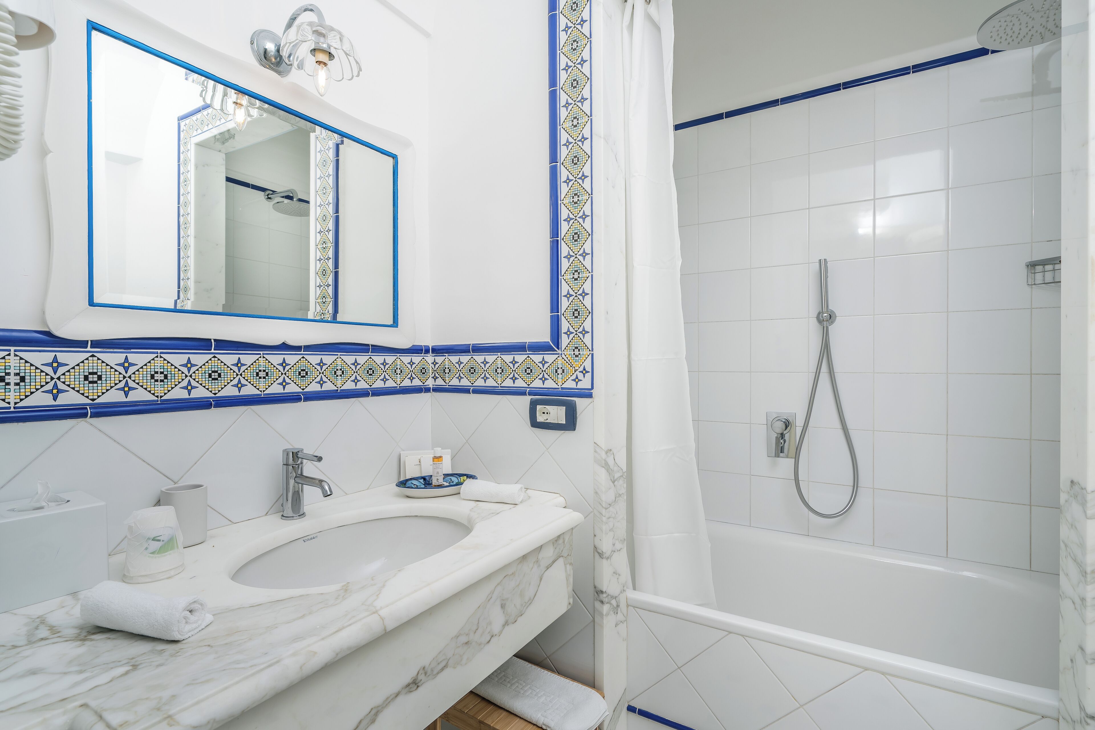 A bathroom with a white sink, mirror, and shower.