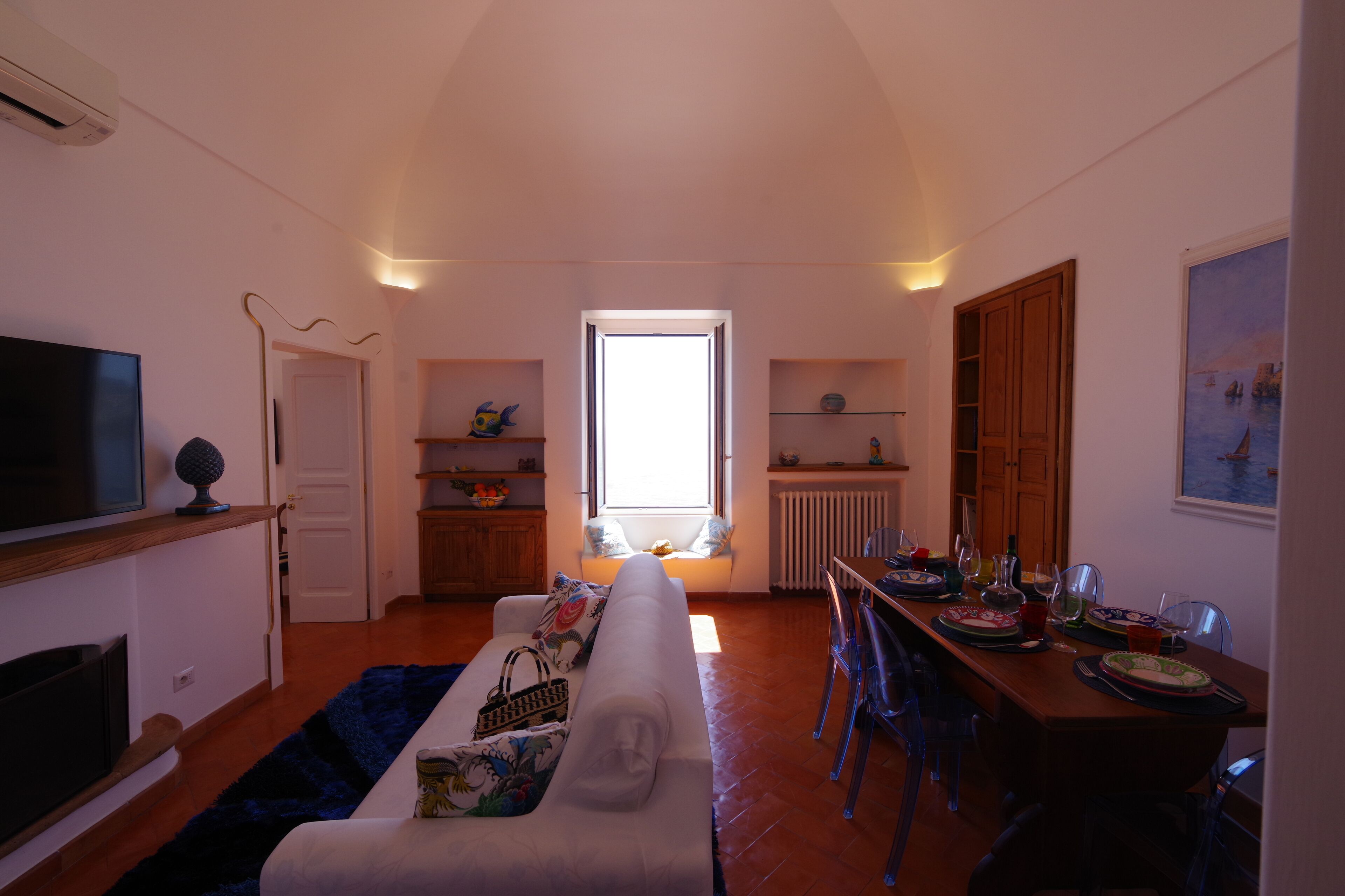 Een woonkamer met een bank, televisie en een eetgedeelte met stoelen en een tafel gedekt voor een maaltijd.