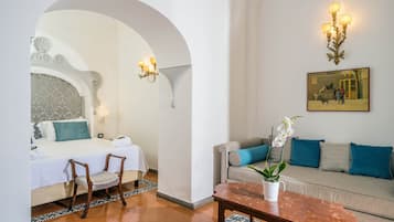 Una habitación de hotel con cama, sofá, mesa de centro y un cuadro en la pared.
