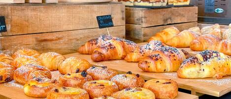Una selezione di prodotti da forno esposti su assi di legno, tra cui pasticcini e pane.