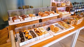 Une vitrine de boulangerie présentant divers produits de pâtisserie, comme des croissants, des muffins et des tartes.