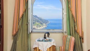 A room with a view of a coastal landscape through a window with striped curtains. - Hotel Bonadies (Ravello)