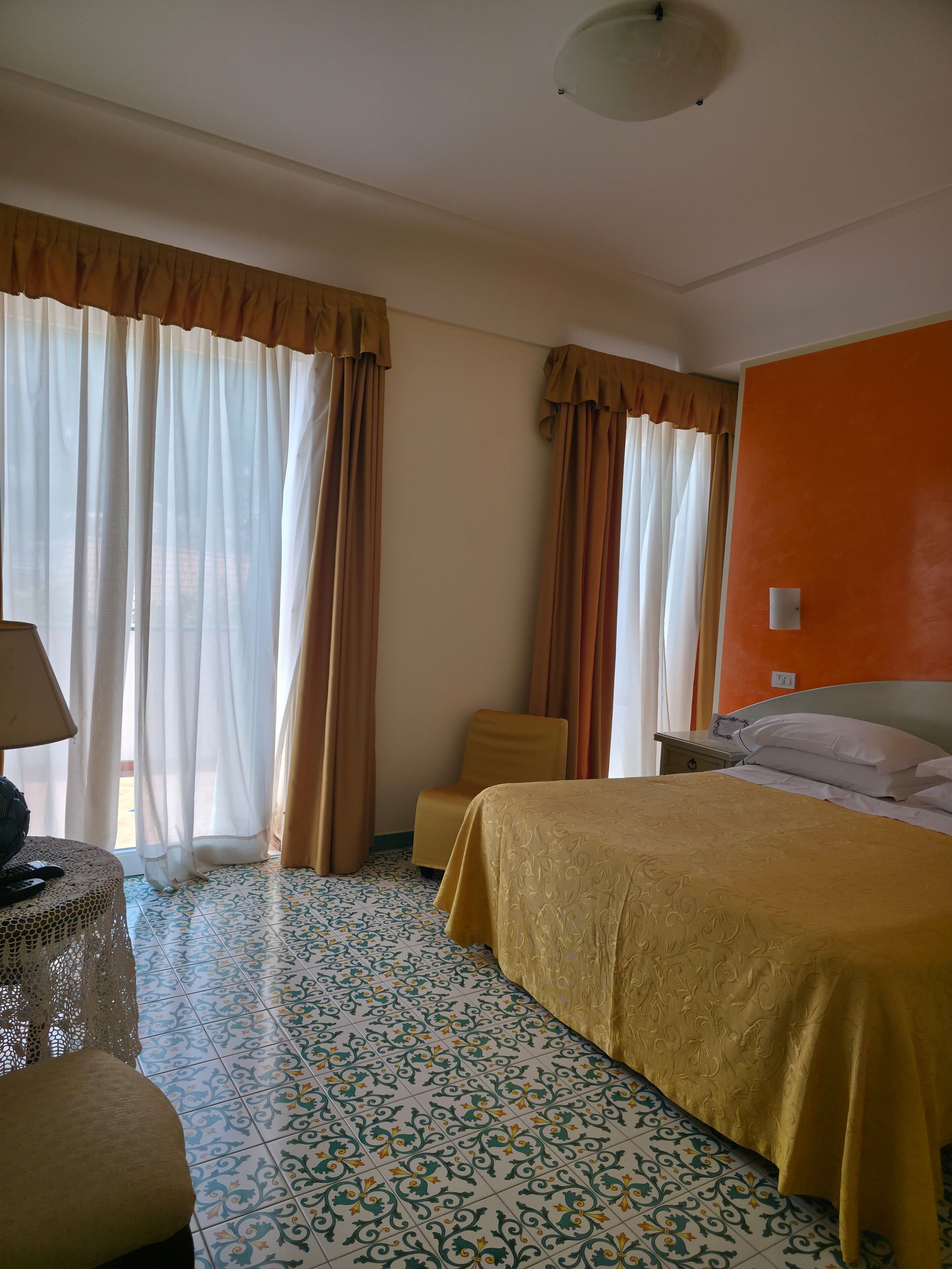 Una habitación de hotel con una cama, una silla, una mesita de noche y una lámpara.