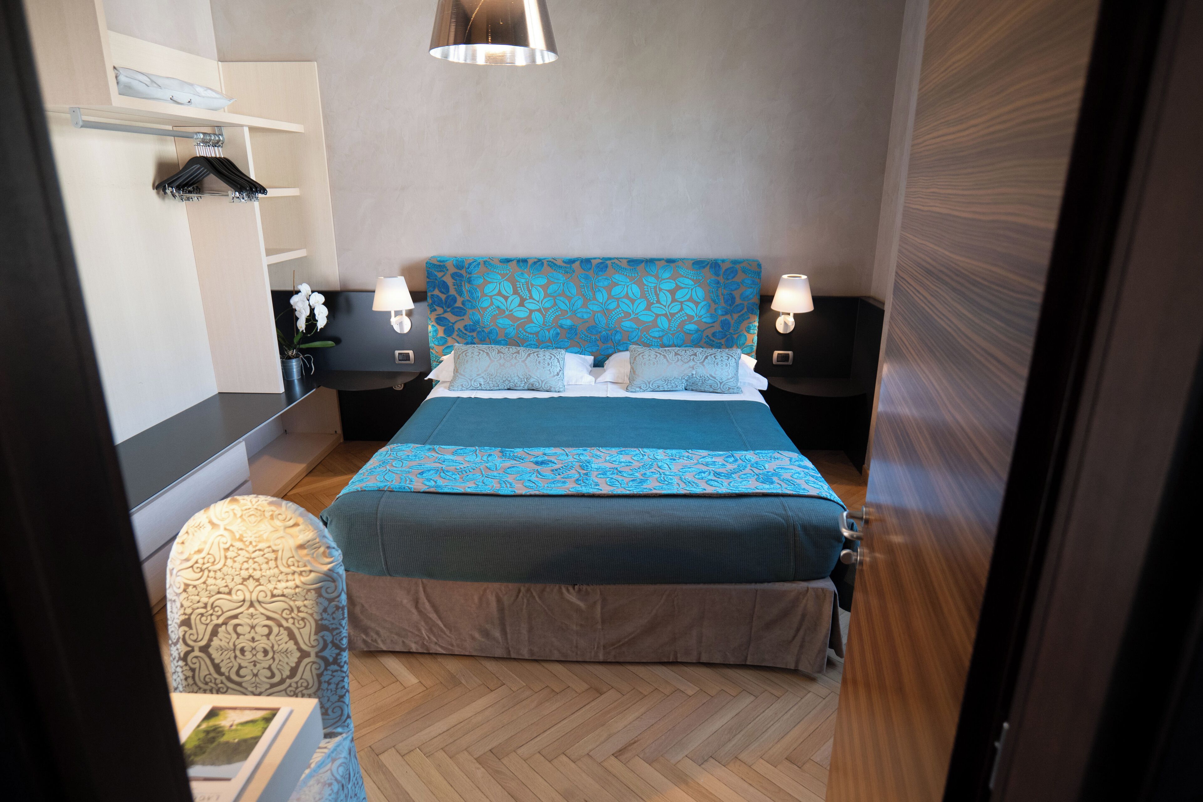 Ein modernes Schlafzimmer mit einem großen Bett, Nachttischlampen, einem Kleiderschrank und einem kleinen Tisch mit einem Buch.