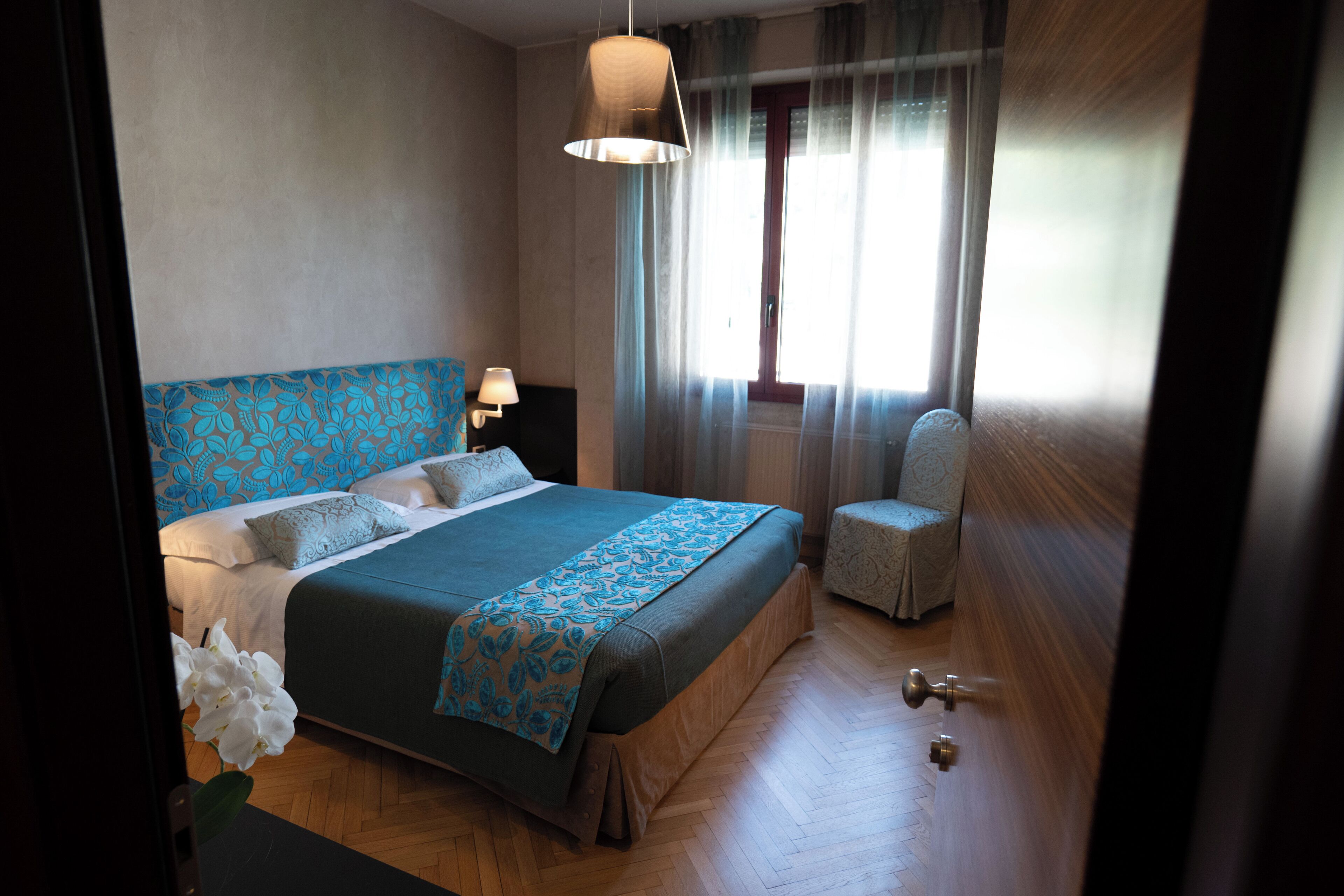 A bedroom with a bed, a chair, a lamp, and a window with curtains.
