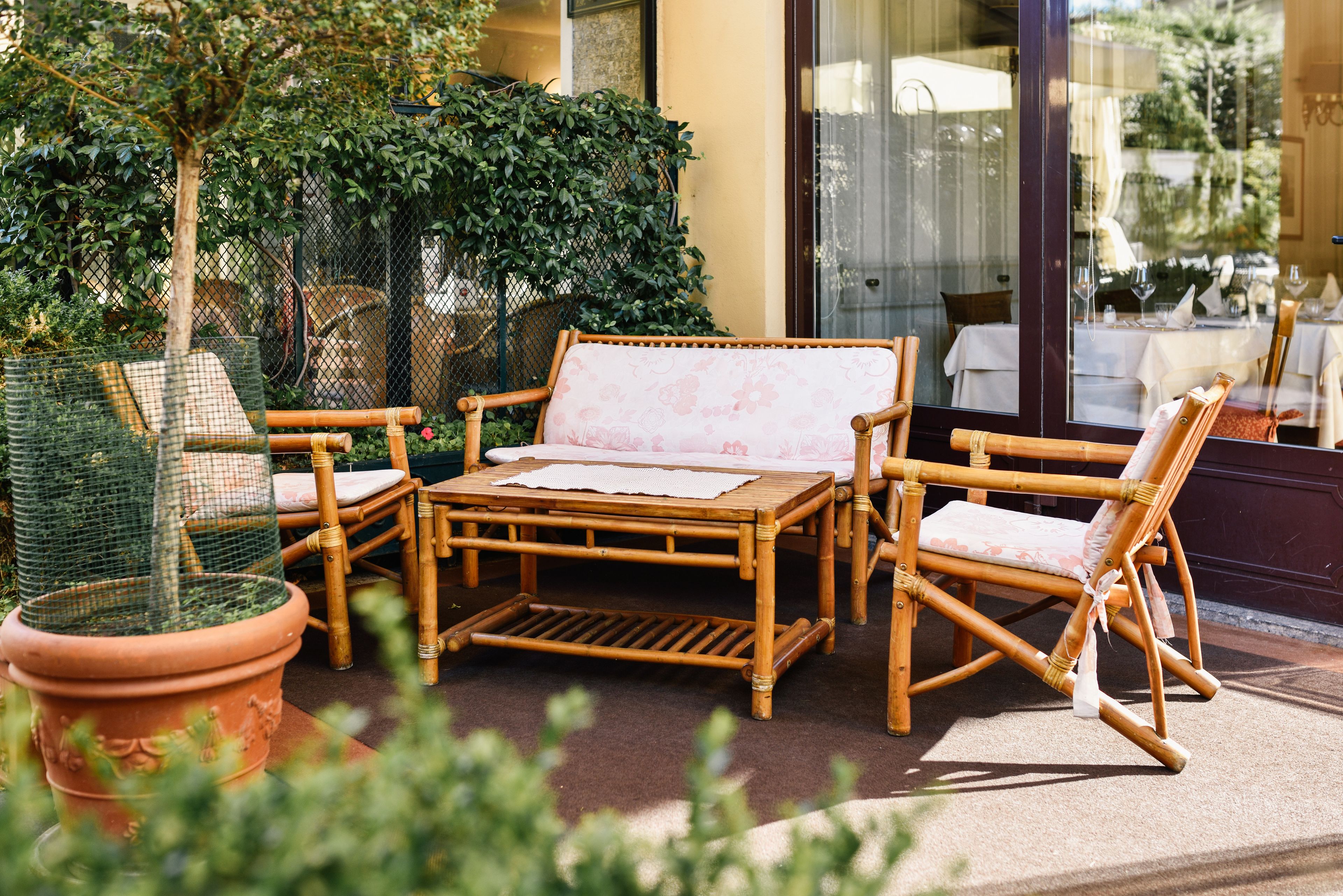An outdoor seating area with wicker furniture, a table, and potted plants.