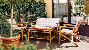 An outdoor seating area with wicker furniture, a table, and potted plants.