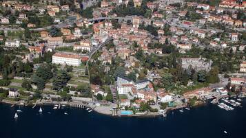 An aerial view of a coastal town with a marina, buildings, and greenery.