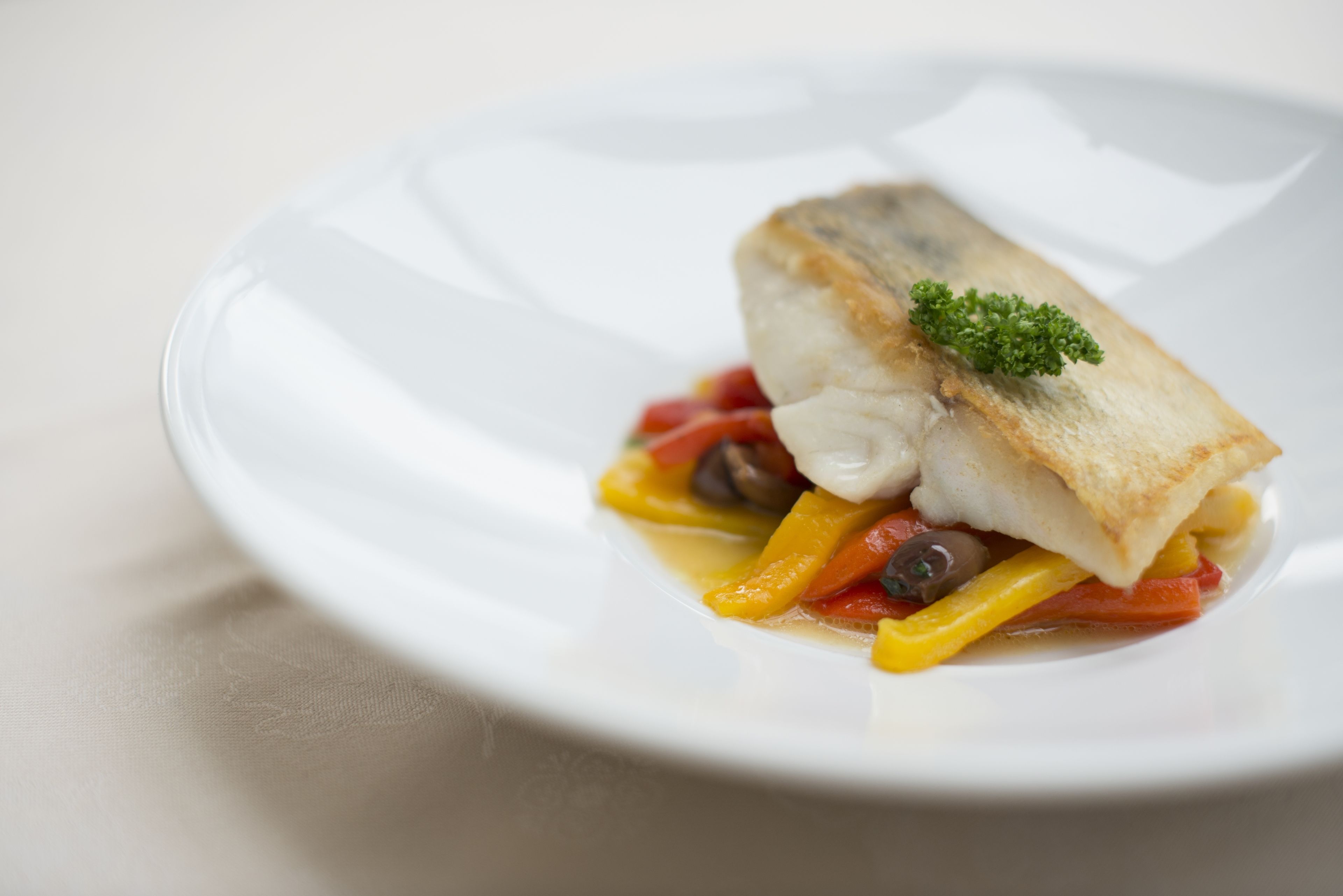 Une assiette blanche avec un morceau de poisson et des légumes.
