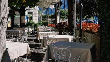 Un café en plein air avec des tables et des chaises, entouré de plantes et de fleurs.