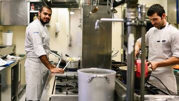 Uma cozinha profissional com eletrodomésticos de aço inoxidável e chefs de uniforme branco.