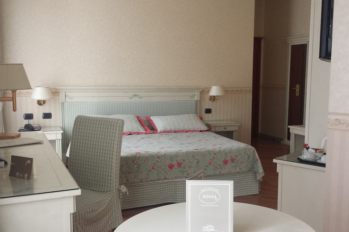 Ein Hotelzimmer mit Bett, Schreibtisch, Stuhl, Lampe und einem Schild mit der Zimmernummer.