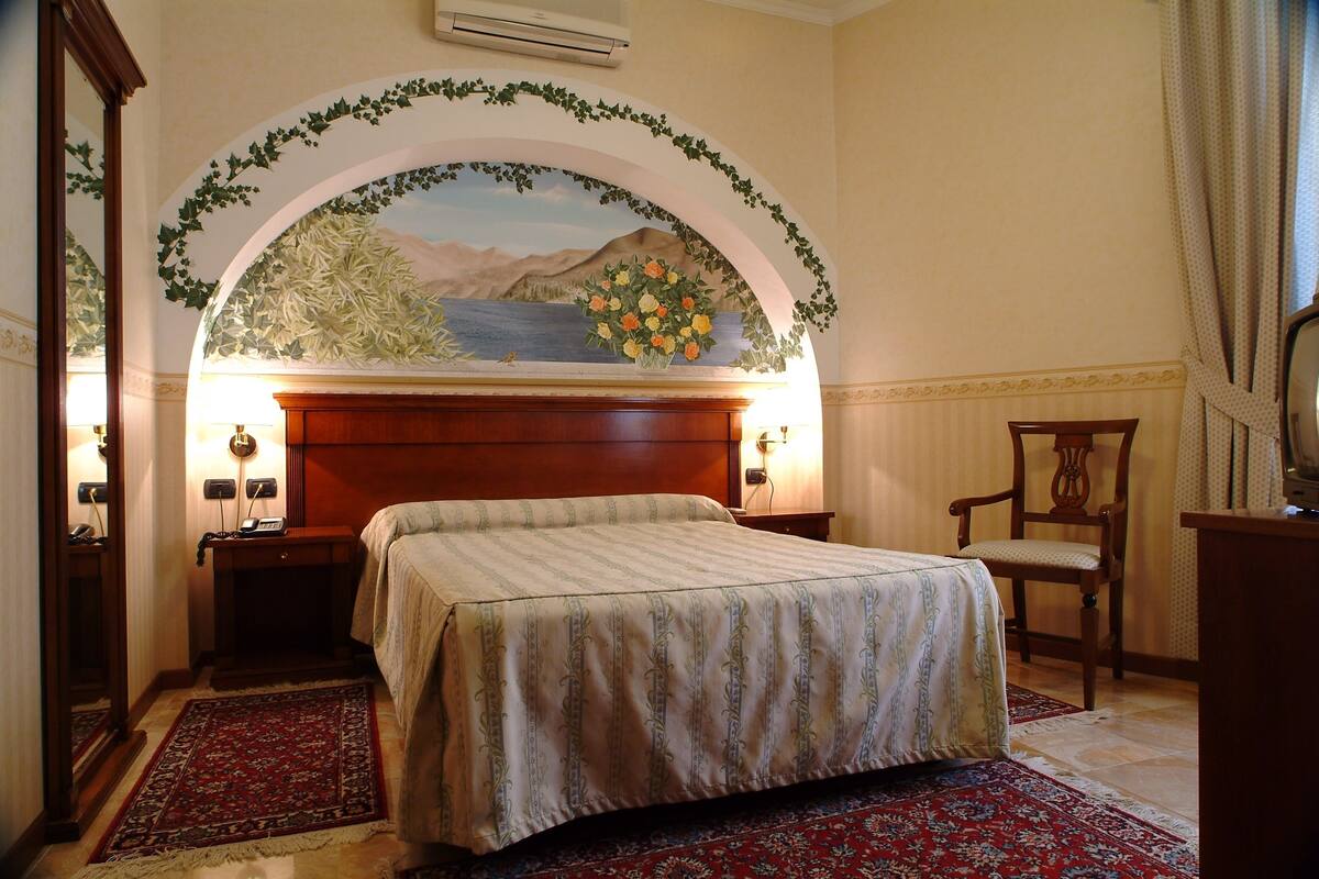 Ein Hotelzimmer mit Bett, Nachttisch, Stuhl und Schreibtisch.