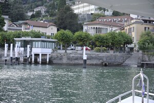 A waterfront building with a dock, a flag, and a bell.